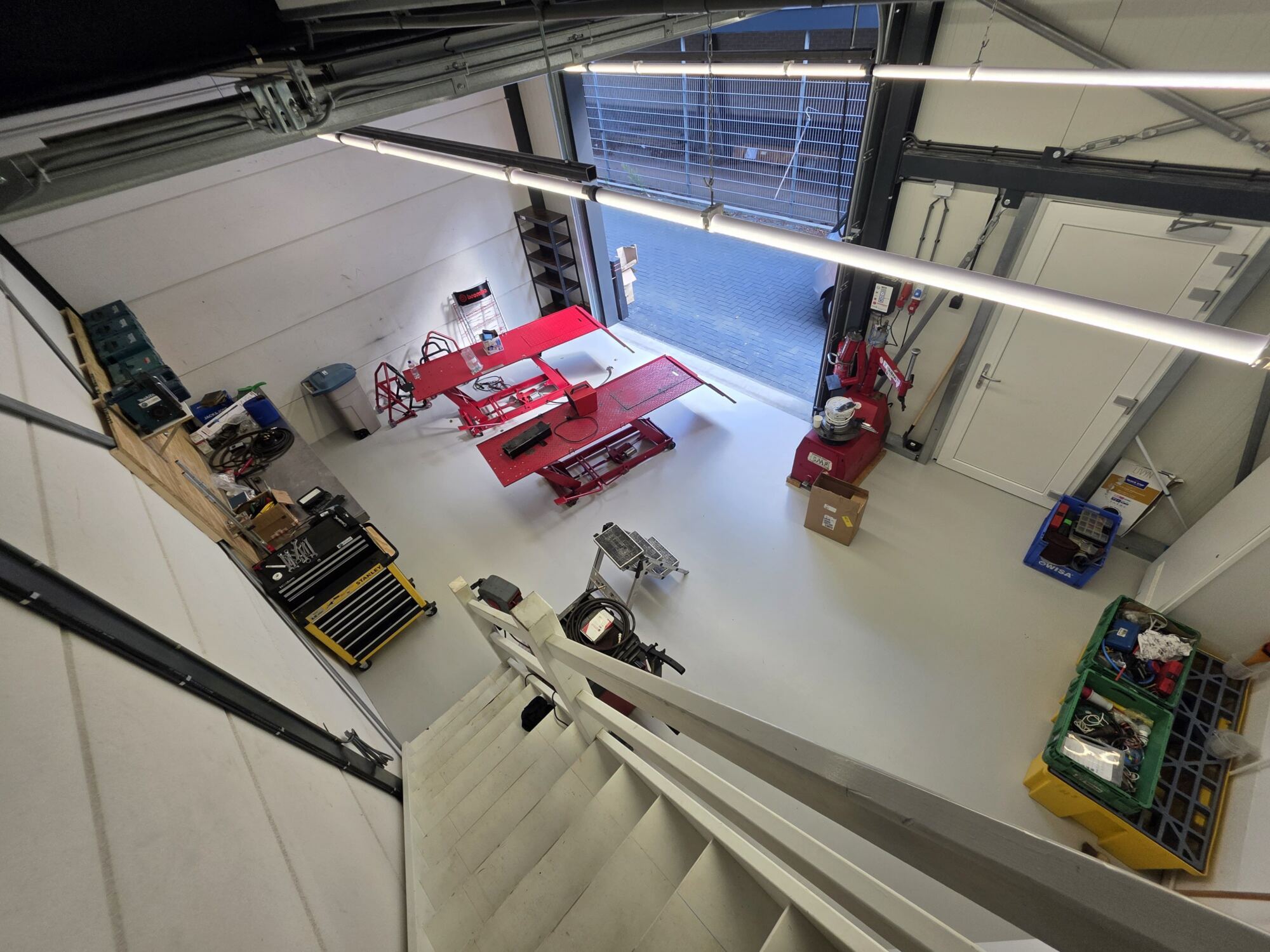 De werkplaats van VD Toorn Motorservice in Alkmaar met twee rode heftafels en een bandenwisselmachine