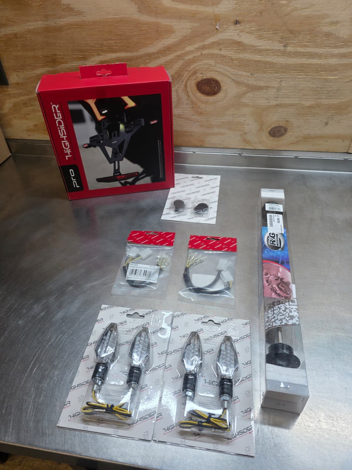 Verpakte accessoires zoals knipperlichten en een kentekenplaathouder op de werkbank